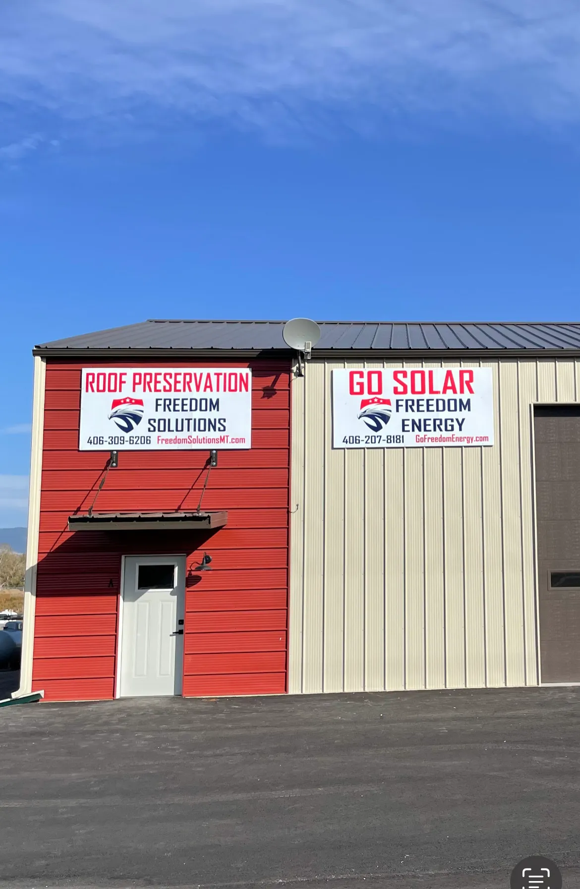 A building with red and beige siding displays two large signs. The left sign advertises Roof Preservation Freedom Solutions, and the right sign advertises Go Solar Freedom Energy, each with contact info.